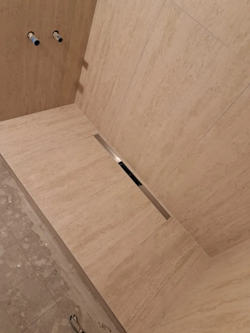 Walk-in-Dusche in Travertinoptik mit Linienentwässerung